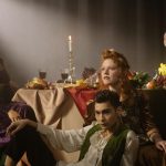 Grupo de pessoas com roupas elegantes posa ao redor de uma mesa decorada em ambiente sofisticado.