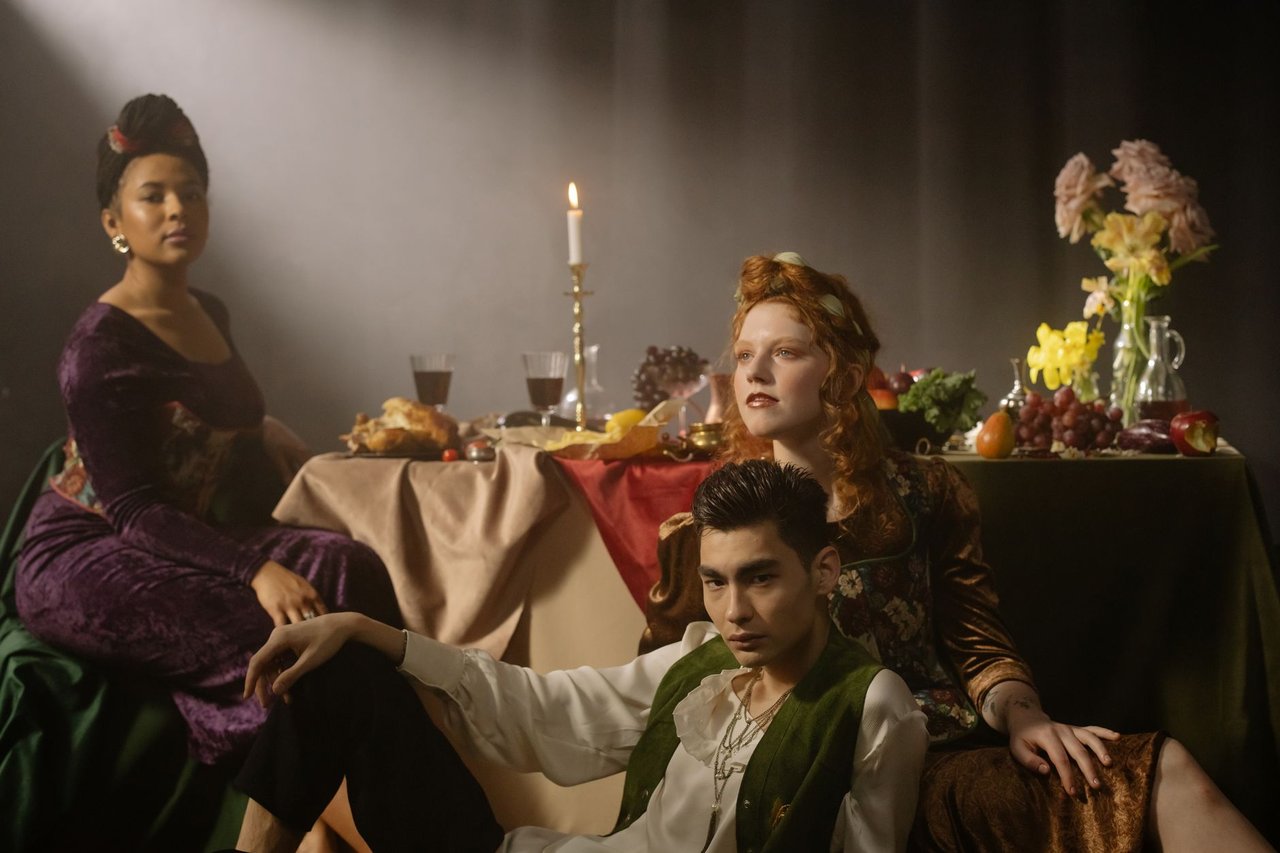 Grupo de pessoas com roupas elegantes posa ao redor de uma mesa decorada em ambiente sofisticado.
