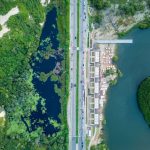 Vista aérea de área urbana junto ao litoral, com estrada, vegetação e faixa costeira em Fortaleza.