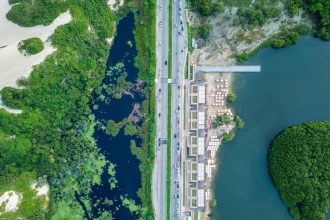 Vista aérea de área urbana junto ao litoral, com estrada, vegetação e faixa costeira em Fortaleza.